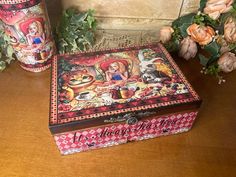 a decorative box sitting on top of a wooden table next to vases and flowers