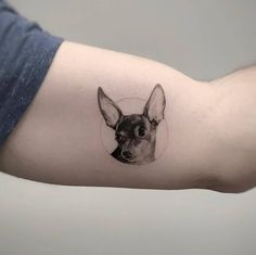 a small black and white dog tattoo on the left inner arm, with a circle around it's head