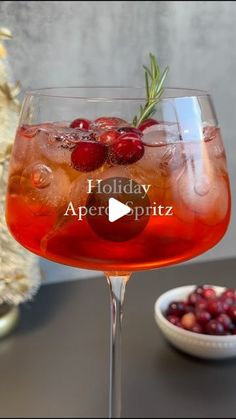 the holiday aperolpitz cocktail is garnished with cranberries and rosemary