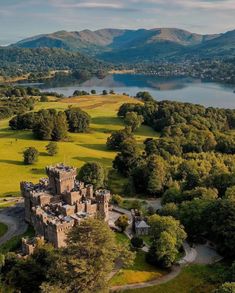 an aerial view of a castle in the middle of a field with trees and mountains