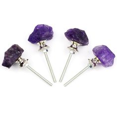 four purple crystal stones with silver tips on white background, three are in the shape of rock