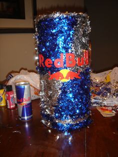 a red bull can sitting on top of a wooden table covered in tinsels