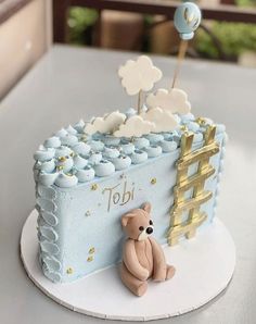 a blue and white cake with a teddy bear sitting on the side next to it