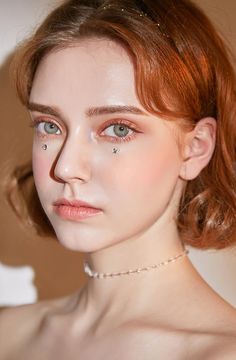 a woman with red hair wearing a pearl necklace