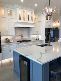 a large kitchen with white cabinets and marble counter tops, an island in the middle