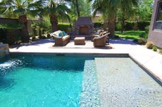 an outdoor pool with lounge chairs next to it and palm trees in the back ground