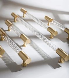 several gold and clear glass handles on a white surface