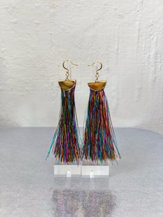 Gift yourself or a friend a unique set of rainbow metallic tinsel tassel earrings for a special occasion. They feature 18K gold and a rainbow tinsel fringe that dangle perfectly from your ears for a spectacular look. Fringe is very soft! Materials: 18K gold hook, gold half moon, rainbow tinsel fringe Fringe Length: 3in Festival Multicolor Tassel Earrings With Dangling Beads, Multicolor Handwoven Tassel Drop Earrings, Tinsel Tassel, Rainbow Tassel Dangle Earrings, Rainbow Fringe Dangle Earrings, Multicolor Fringe Dangle Earrings, Moon Rainbow, Fringe Earrings, Tassel Earrings