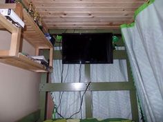 there is a tv on the wall in this small room with bunk beds and curtains