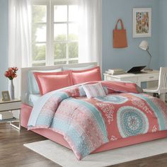 a bedroom with blue walls and pink comforter sets on the bed in front of a window