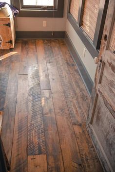 an empty room with wood flooring and a wooden door in the center, looking out to outside