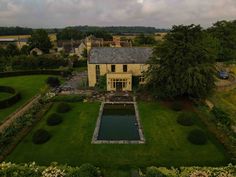 an aerial view of a large house with a pool in the middle and lots of greenery around it