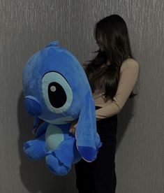 a woman is holding a large blue stuffed animal