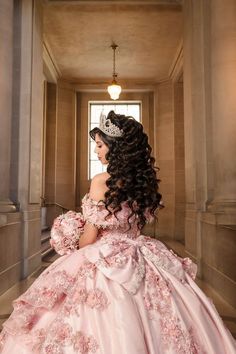 a woman in a pink dress and tiara is looking out the window with her back to the camera