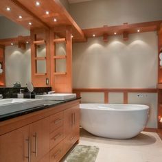 a large bath tub sitting in the middle of a bathroom next to two sink basins