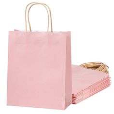 pink paper bags stacked on top of each other in front of a white background with wicker handles