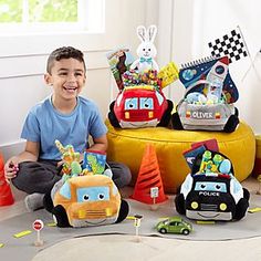 a little boy sitting on the floor with some toys in front of him and smiling at the camera