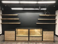 an empty room with wooden shelves and lights on the ceiling, in front of a black wall