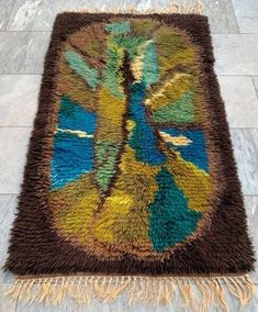 a multicolored area rug with fringes on the bottom and an image of a tree