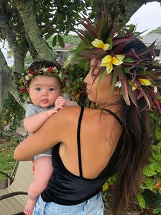 a woman holding a baby in her arms and wearing a flower crown on her head