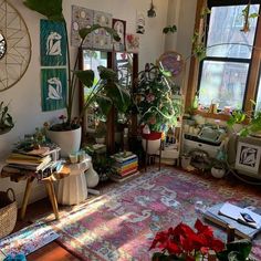 a living room filled with lots of plants next to two windows and a rug on the floor