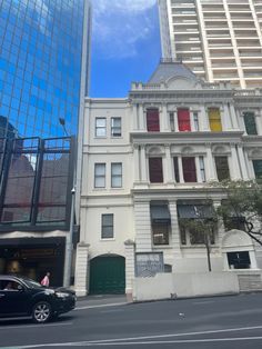 a black car is parked in front of an old building with red and yellow shutters