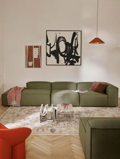 a modern living room with green couches and orange chairs in front of a painting on the wall