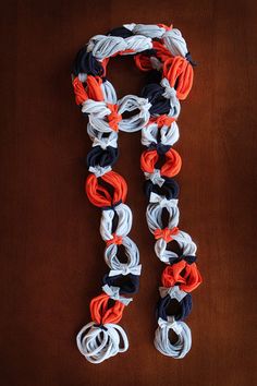 an orange, white and blue scarf on a wooden table next to a cell phone