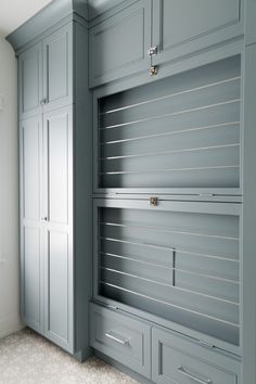 an empty room with gray cupboards and white carpeted flooring on the walls