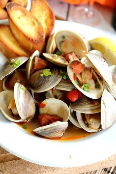 a white plate topped with clams and bread