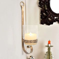 a candle that is sitting on a shelf next to a mirror and christmas tree in a vase