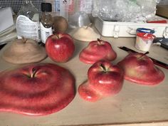 some apples are sitting on a table with knifes and other items around them in the background