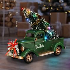 an old green truck with a christmas tree on the bed and presents in the back