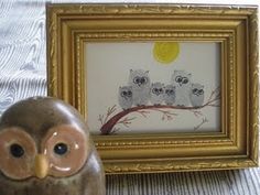 an owl figurine sitting next to a framed painting