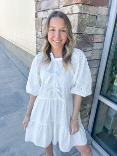 Add a touch of elegance to your wardrobe with the Chic Moment Eyelit Bow Tier Dress in white. This dress features delicate eyelit detailing and a charming bow, making it the perfect choice for any occasion. You'll feel confident and lovely in this stylish and sophisticated piece! Ashlyn is wearing a size small, which is her typical size for dresses! White Casual Eyelet Dress, White Eyelet Dress For Brunch, White Broderie Anglaise Mini Dress For Brunch, White Eyelet Dress For Spring, White Mini Dress With Bow For Day Out, Spring Elegant Eyelet Mini Dress, Chic White Eyelet Mini Dress, Elegant Spring Mini Dress With Eyelet Details, Elegant Spring Mini Dress With Eyelets