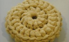 a crocheted object is shown on a white surface with a black button in the center