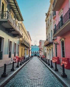 a cobblestone street lined with colorful buildings and red benches in the middle of it