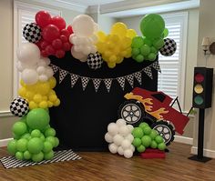 a birthday decoration with balloons and cars on the floor in front of a black bucket