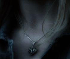 a close up of a person wearing a necklace with an owl on it's back