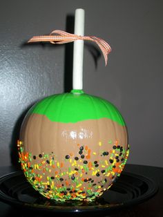 a painted pumpkin with sprinkles on it sitting on a black platter