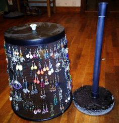 a black trash can with earrings on it and a blue pole next to it in the middle of a wooden floor