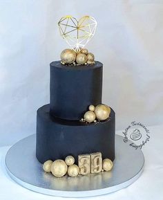 a three tiered black cake with gold decorations