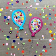 two balloons with confetti attached to them on a floor covered in confetti