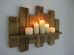 several candles are lit on a wooden shelf