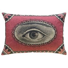 a red pillow with an eye on the front and pink, black and white background