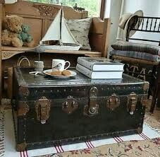 an old trunk is sitting on the floor next to a coffee table and teddy bear