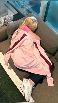 a woman laying on top of a couch next to a window