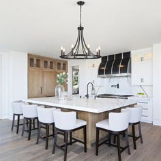 a kitchen with an island and white chairs