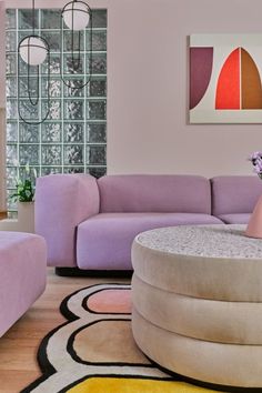 a living room filled with purple couches next to a white coffee table and colorful rugs