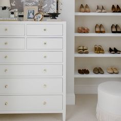 a white dresser sitting next to a wall filled with shoes